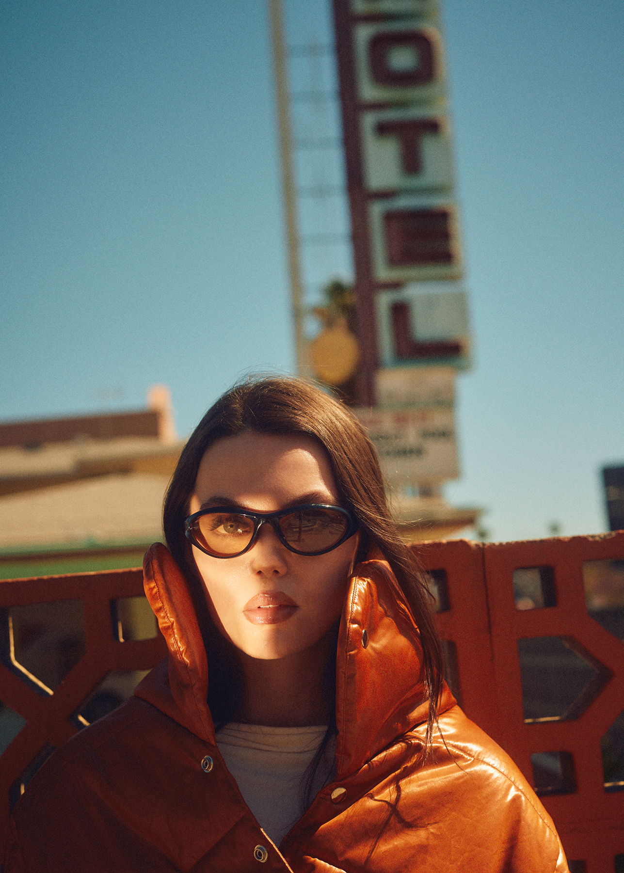 Portrait of Caroline Cummings against a blue sky in sunglasses with a beam of light across her face as she makes eye contact with the camera